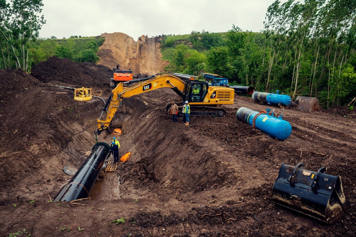 Excavator laying large underground pipeline in a trench
