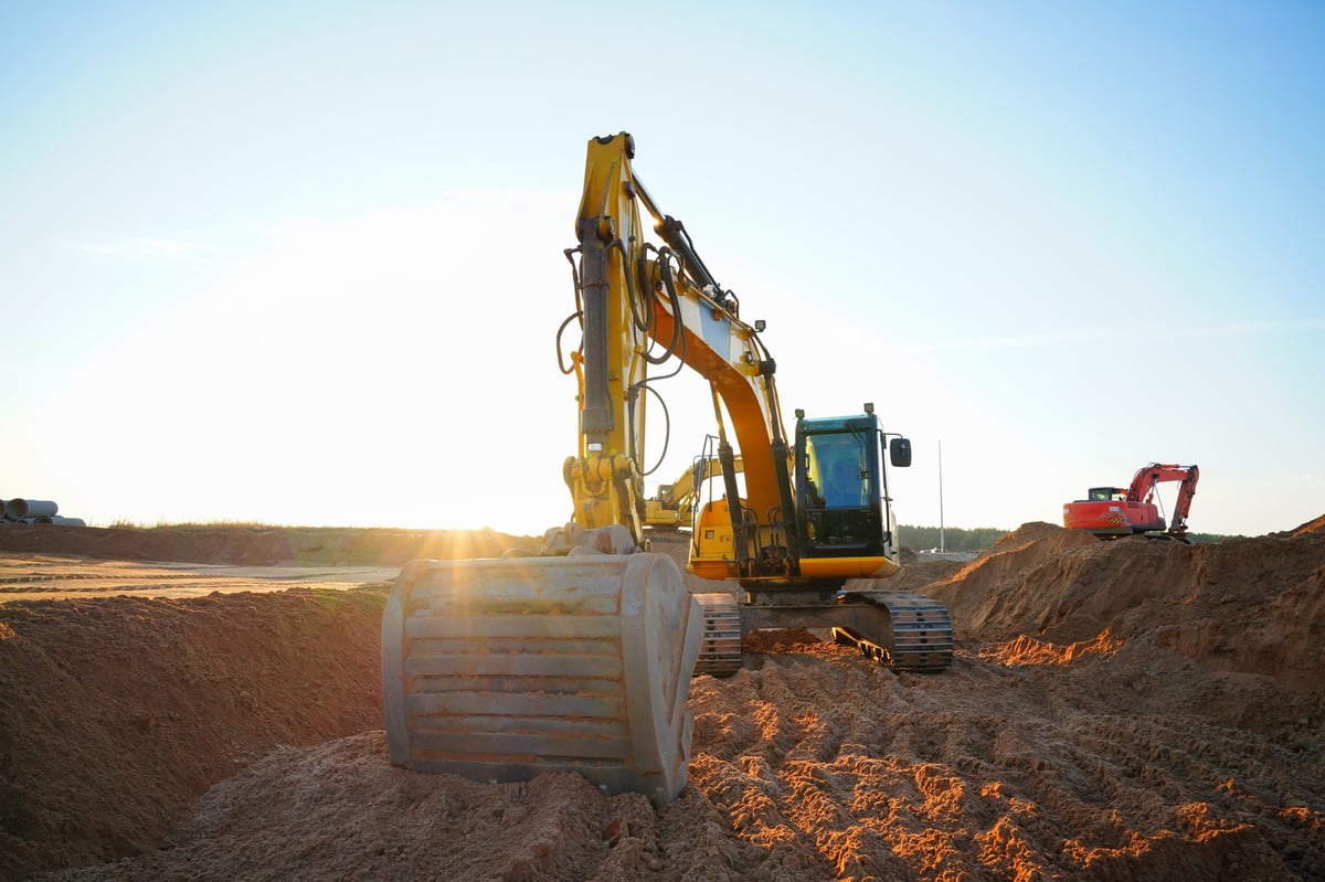 Excavator digging a trench for sewer and water line replacement