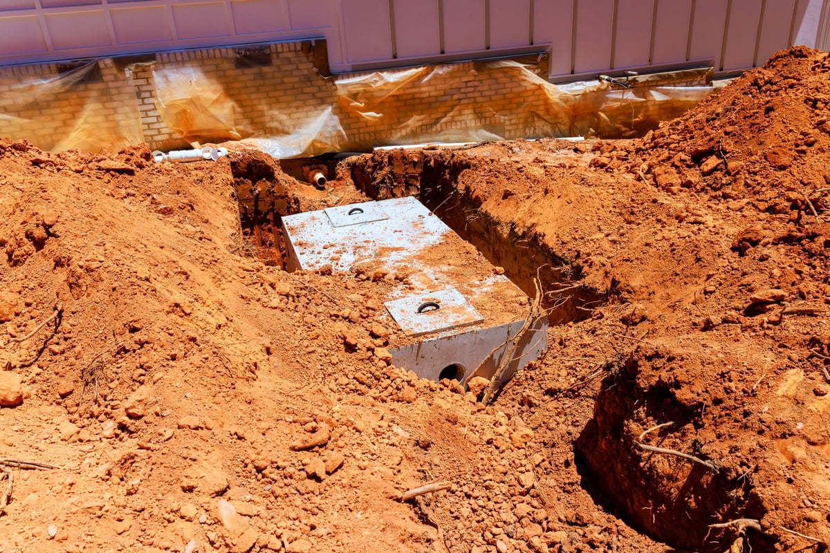Workers at a construction site where concrete septic tanks are buried under dirt in a residential area