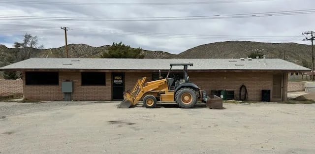 Yellow wheel loader parked in front of a brick building in a desert landscape with hills in the background